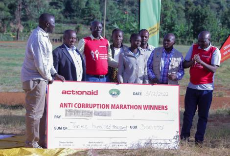 AAIU Country Director, Xavier Ejoyi, hands of a cash prize at the Anti-Corruption Marathon in Kween.