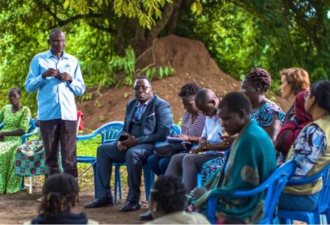 A photo of James Okot(standing) a war survivor narrating his journey of access to land Justice through court