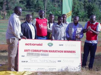 AAIU Country Director, Xavier Ejoyi, hands of a cash prize at the Anti-Corruption Marathon in Kween.