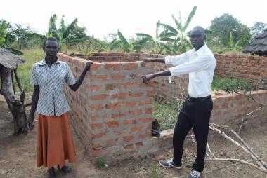 Emorut and his mother pose for a photo in front of their house that is under construction.